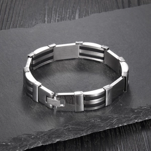 Detailed close-up of men's stainless steel and black silicone bracelet on a stone texture