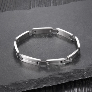 Macro shot of brushed stainless steel link bracelet on natural dark stone surface