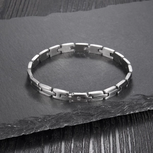 Minimalist silver stainless steel chain link bracelet with brushed finish on rock surface