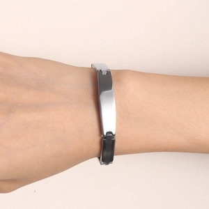 Minimalist silver-toned metal bracelet with polished rectangular bar on a warm background