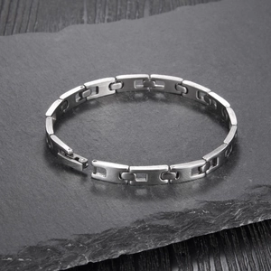 Close-up of a delicate stainless steel chain bracelet with rectangular hollow links on stone