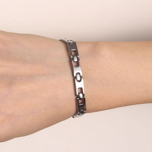Minimalist silver stainless steel link bracelet worn on wrist over a soft pastel background