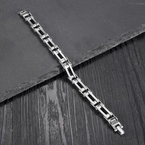 Polished stainless steel men's bike chain bracelet on dark slate and wood surface