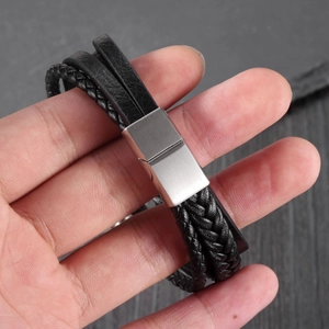 Detail of multi-layer black braided leather bracelet with silver magnetic clasp