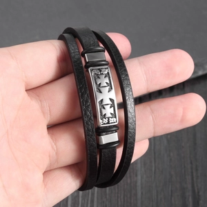 Detail of multi-layer black leather bracelet with engraved silver cross metal plate