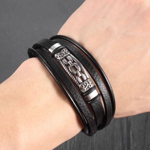 Detail of vintage braided leather bracelet with engraved silver metal charm for men
