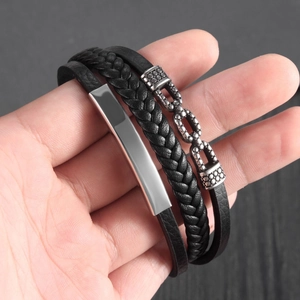 Close-up of men's multi-layer black braided leather bracelet with stainless steel ID plate