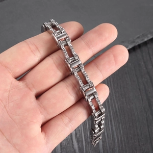 Men's silver stainless steel motorcycle chain bracelet shown on a hand against black stone