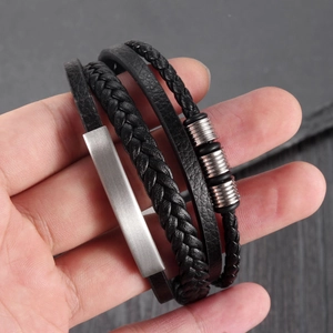 Macro detail of multilayer black braided leather bracelet with brushed steel metal plates