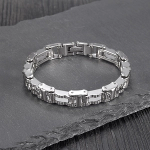 Detailed view of heavy stainless steel motorcycle chain bracelet on dark stone surface