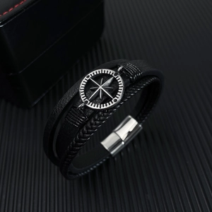 Détail d'un bracelet en cuir tressé multicouche avec boussole argentée et fermoir