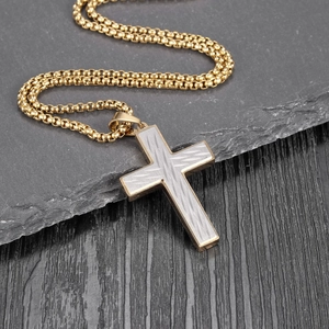 Macro shot of two-tone gold and silver cross pendant with brushed texture and box chain