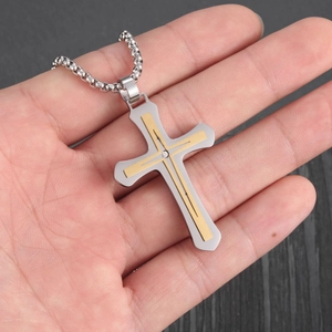Close-up of two-tone stainless steel cross pendant with zircon on beaded metal chain
