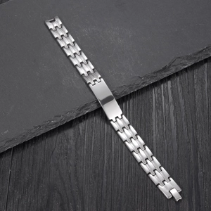 Bracciale da uomo in acciaio inossidabile lucido con piastra su sfondo di pietra scura