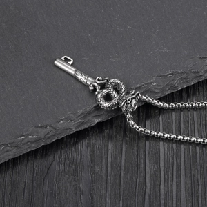 Silver stainless steel dragon snake key pendant necklace on black slate background