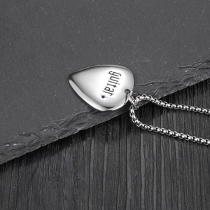 Collana con ciondolo a plettro di chitarra in acciaio inossidabile su sfondo di roccia