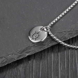 Polished silver titanium steel sun smiley pendant necklace on natural rock background