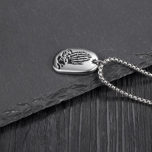 Détail du pendentif crâne mains en prière en titane argenté avec chaîne à mailles