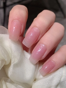 Close-up of pink jelly gradient press-on nails with silver glitter and long square shape