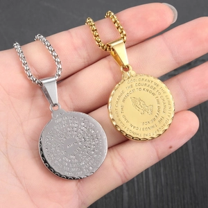 Macro shot of stainless steel pendant with Lord's Prayer engraving and praying hands