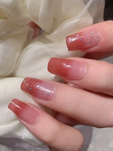 Détail d'ongles adhésifs dégradé rose avec paillettes argentées et sequins brillants