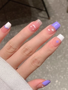 Gros plan sur des faux ongles rose et violet avec smileys blancs et motifs d'étoiles