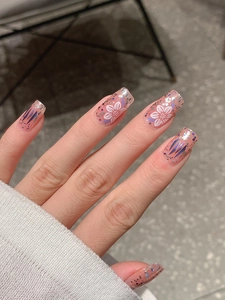 Detail of press-on nails with purple floral patterns and glitter on a knit background