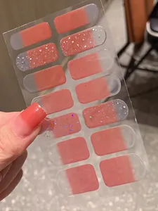 Détail d'autocollants ongles dégradé rose avec paillettes argentées et sequins colorés