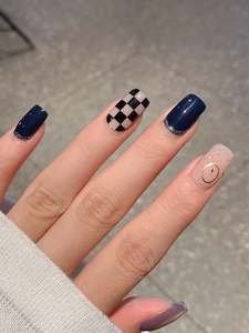 Macro detail of squoval press-on nails with navy glitter, checkered and polka dot designs