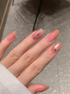Close-up of French gradient orange peach nail wraps with iridescent silver glitter