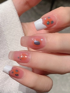 Close-up of square French manicure nail stickers with orange gradient and silver glitter