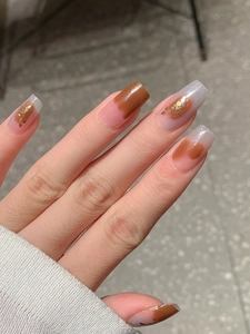 Détail de faux ongles carrés marron et nude avec des touches de feuille d'or