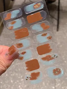 Vue détaillée des stickers ongles bleu et caramel avec feuilles d'or sur les ongles