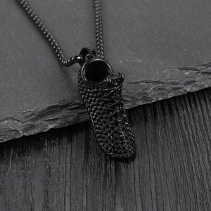 Gros plan d'un pendentif baskets noir en acier inoxydable avec détails texturés