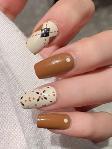 Close-up of autumn brown argyle nail stickers with cozy knit sweater background
