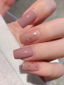 Close-up of dusty rose nail stickers with glitter accents on white knit background