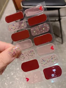 Detail of burgundy Valentine nail stickers with red hearts and pink glitter accents