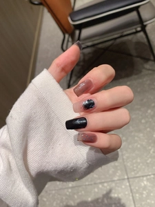 Detail of long square press-on nails featuring black, brown marble and silver glitter designs