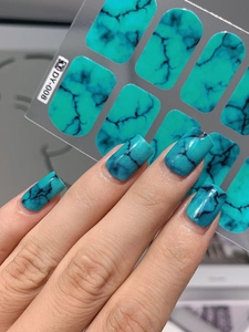 Macro detail of turquoise marble nail stickers showing texture and realistic finger application
