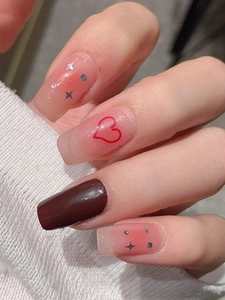 Macro detail of nude pink gradient press-on nails with red hearts and silver stars