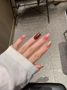 Detail of burgundy and gold glitter press-on nails with star patterns in square shape