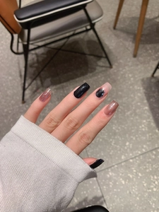 Detail of short square press-on nails with black, glitter pink, and ink art designs