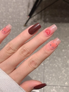Macro detail of burgundy and pink gradient press-on nails with red hearts and silver stars