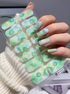 Detailed view of ink marble watercolor nail stickers applied with green and yellow tones