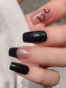 Close-up of long square press-on nails with black hearts, pink base and silver glitter