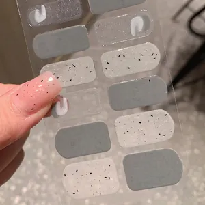 Matte grey and speckled textured nail stickers set with 12 pieces displayed by hand