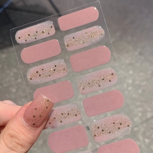 Pink self-adhesive nail stickers with gold glitter accents on a transparent base