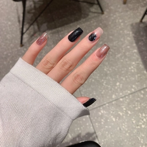 Black and purple glitter press-on nails with marble design on a white sweater background