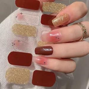 Burgundy and gold glitter nail stickers with blush star design on white knit background