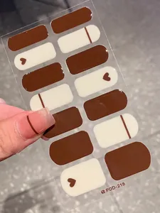 Detail of minimalist dark brown nail wraps with heart and stripe patterns
